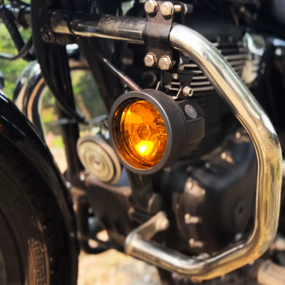 Motorbike with a fog lamp mounted on the side bar, focused on illuminating the road for improved visibility in low-light conditions.